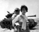 Korea: With her brother on her back, a war-weary Korean girl trudges by a M-26 tank at Haengju. Korean War (1950-1953).